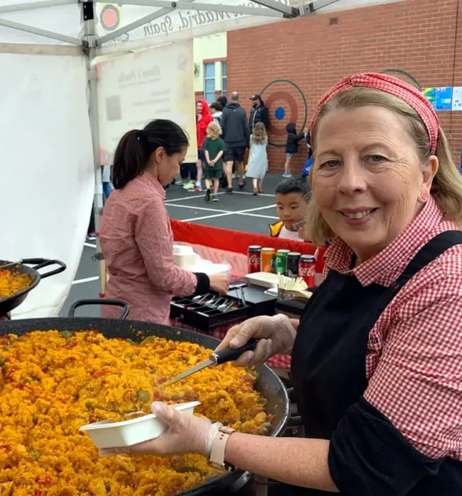 Elena serving freshly cooked paella at a community event