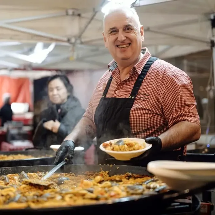 Paella chef serving a fresh portion from the pan