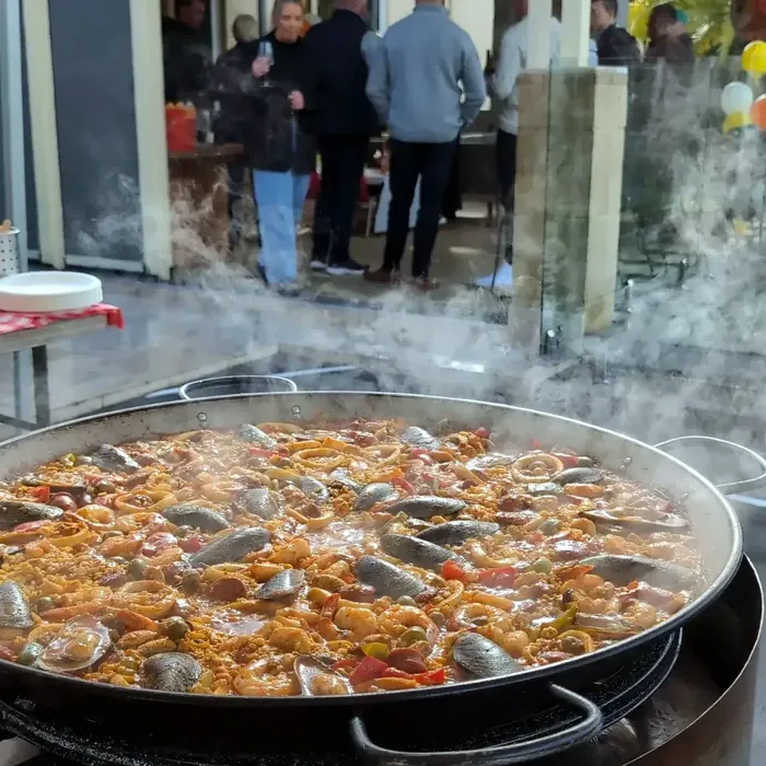 Fresh paella cooking while guests gather nearby