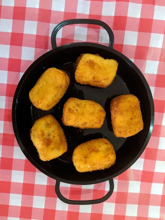 Golden Spanish croquettes served in a small paella pan